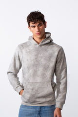 Men's slim fit long sleeve hoodie in a grey tie-dye pattern paired with blue jeans.