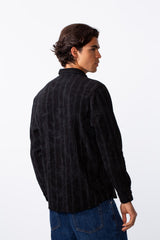 Rear view of a man wearing a black velvet slim fit long sleeve shirt with vertical grey stripes.