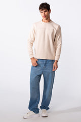 Men's plain essential round neck slim fit sweatshirt in beige paired with blue jeans.