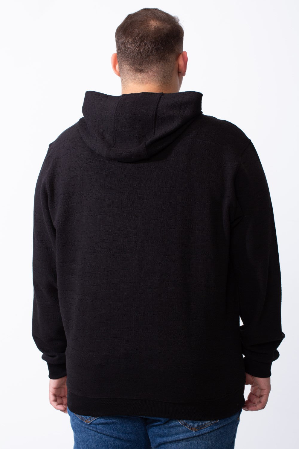 Rear view of a man wearing a black long-sleeve big size hoodie with blue jeans.