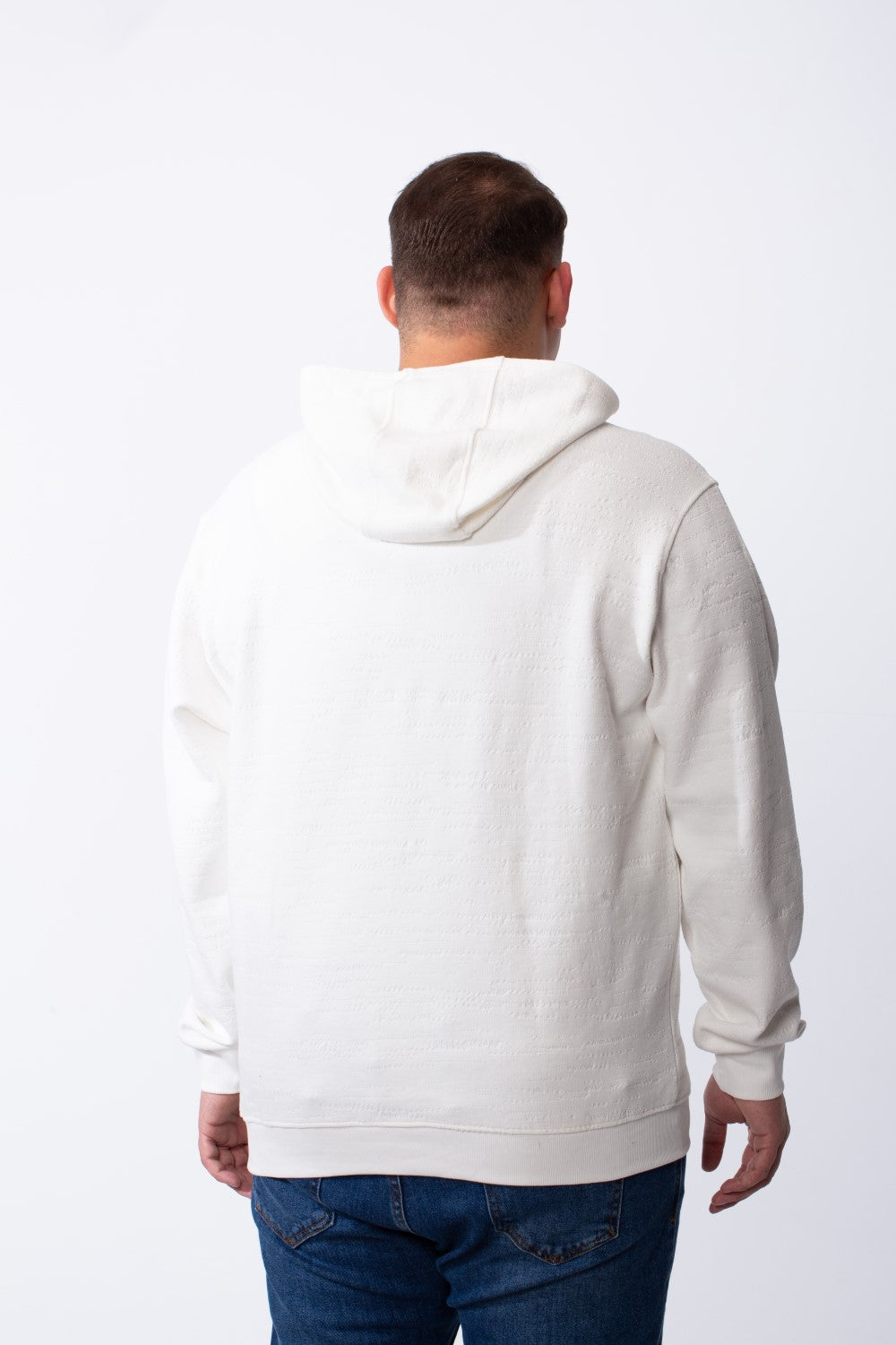 Rear view of a man wearing a white long-sleeve big size hoodie with blue jeans.