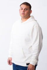 A man wearing a white long-sleeve big size hoodie with a kangaroo pocket and blue jeans.