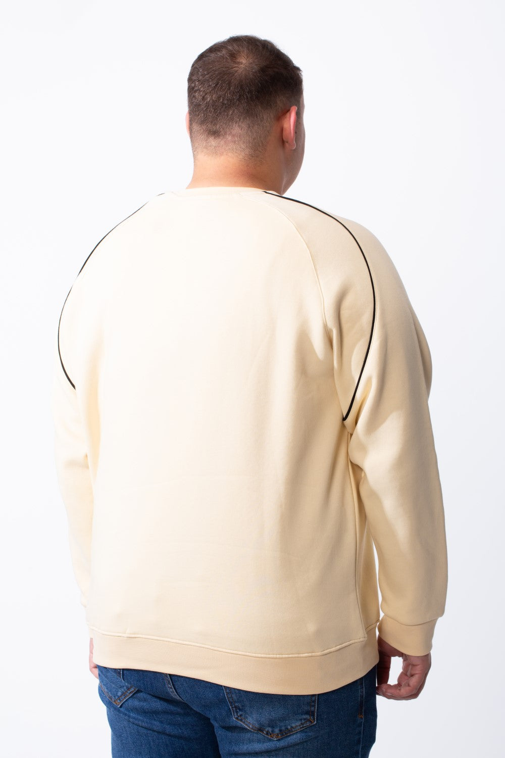 Rear view of a man wearing a cream-colored big size melton sweatshirt with black piping details.