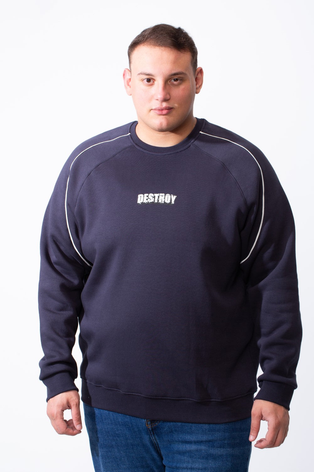 A man wears a navy blue big size crew neck sweatshirt with white piping and a DESTROY graphic.