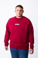 A man wears a big size tomato red crew neck sweatshirt with black piping and a chest graphic.