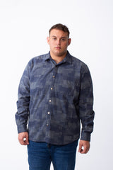 A man wears a big size blue geometric patchwork button-down shirt with a chest pocket.