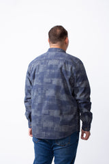 A man from behind wearing a big size blue geometric patchwork button-down shirt and jeans.