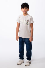 Boy's ribbed crew neck t-shirt in light beige with a playful graphic, paired with blue jeans.