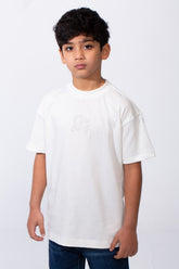 A boy wears a white oversized crew neck t-shirt with subtle typography embroidery on the chest.