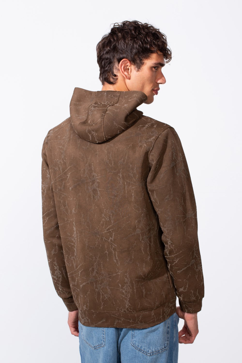 A man from behind wearing a brown tie-dye slim fit long sleeve hoodie and blue jeans.