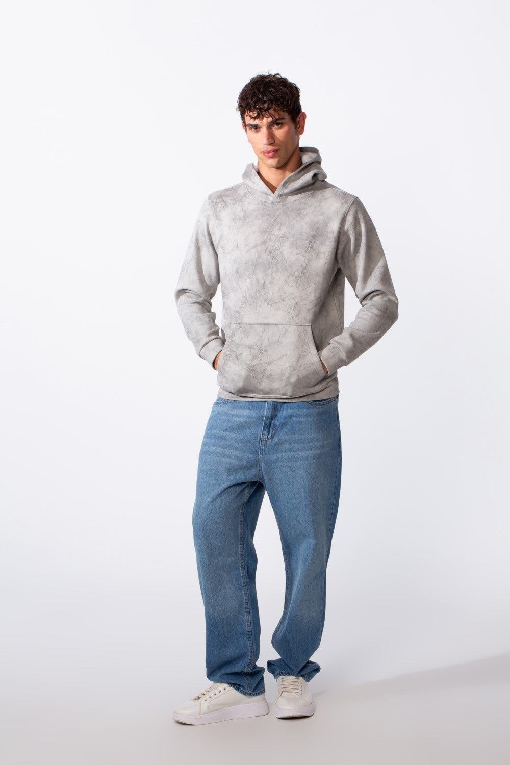 Men's tie-dye long sleeve slim fit hoodie in grey paired with blue jeans and white sneakers.