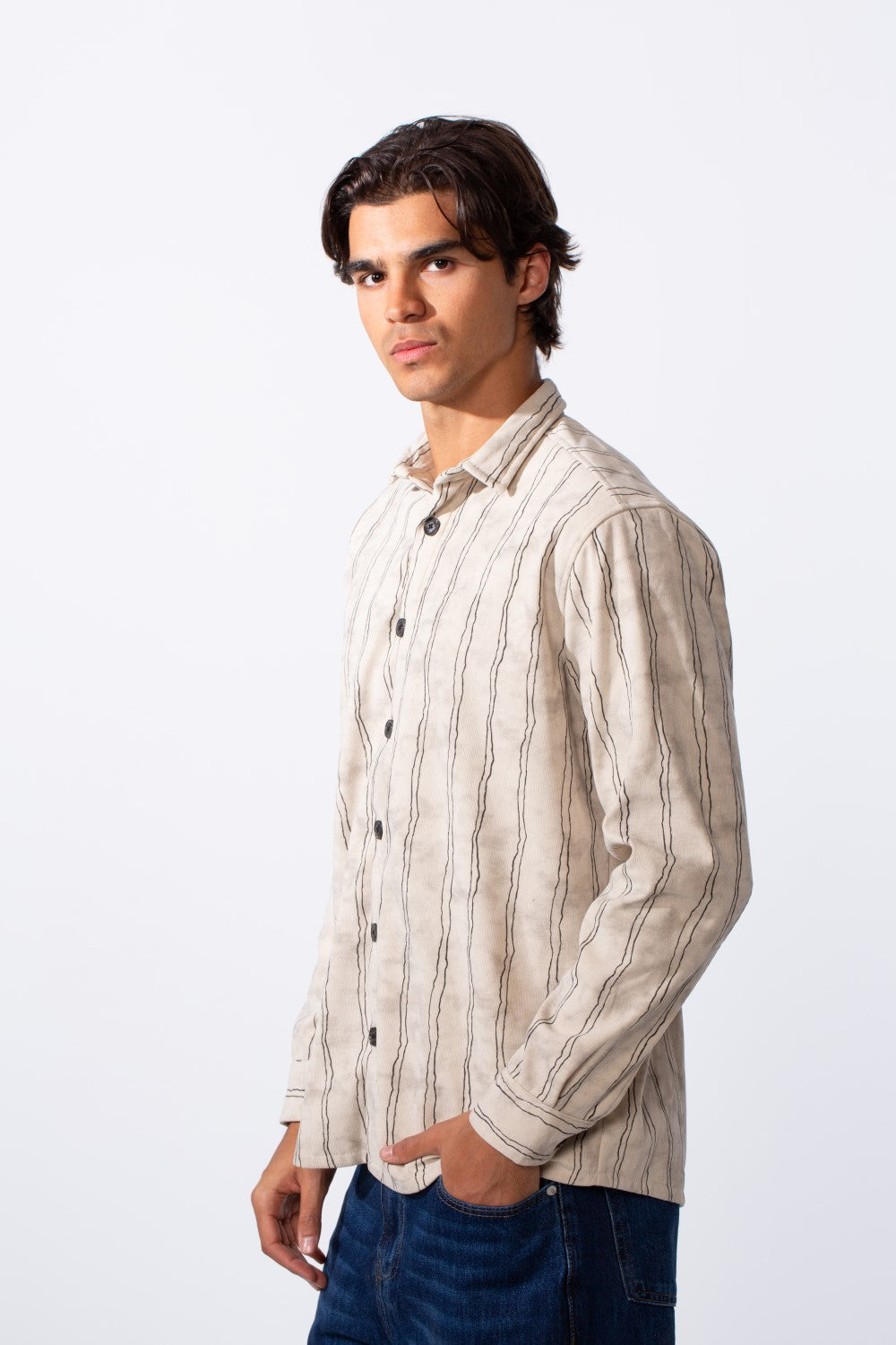 A man wears a slim fit long sleeve velvet shirt with vertical stripes and dark buttons.