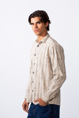 A man wears a slim fit long sleeve velvet shirt with vertical stripes and dark buttons.