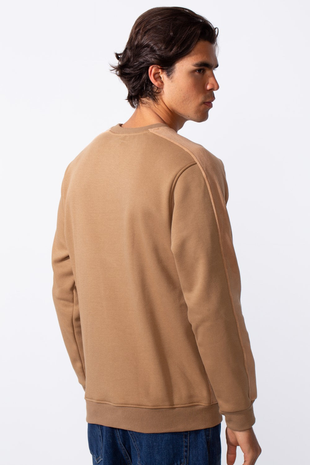 Rear view of a man wearing a tan slim-fit round neck sweatshirt with ribbed cuffs and hem.
