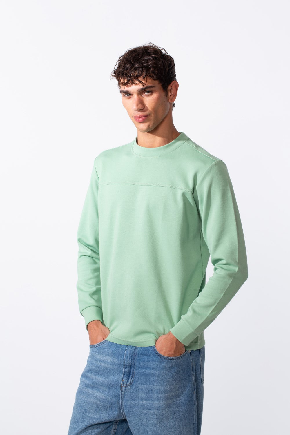 Men's plain mint green round neck slim fit sweatshirt paired with blue jeans.