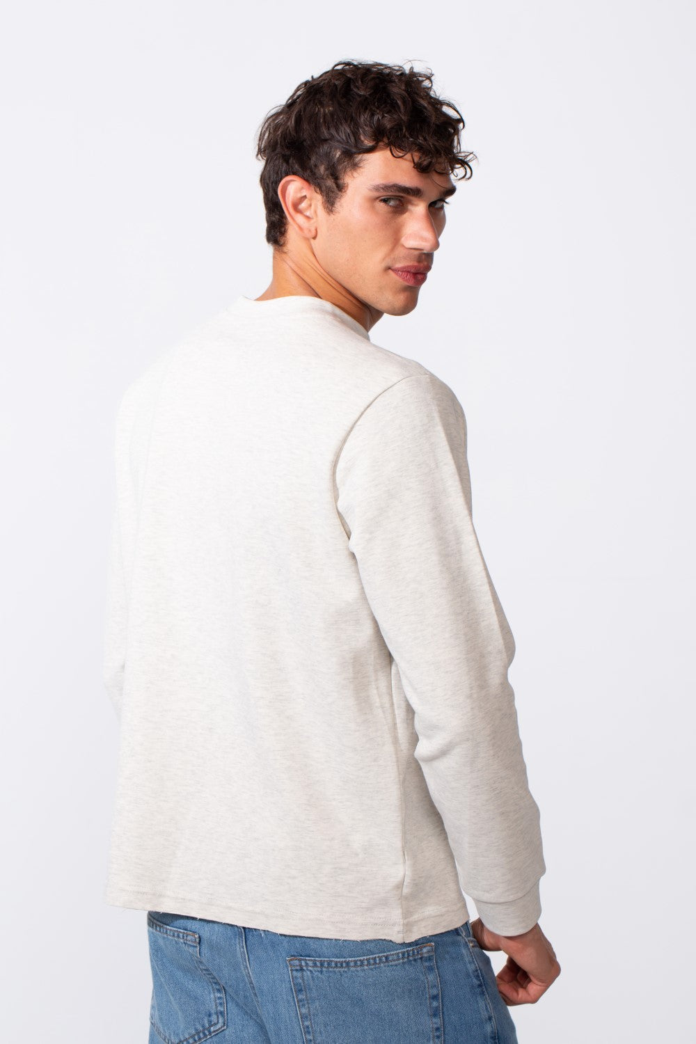 Rear view of a man wearing a light grey slim fit round neck sweatshirt and blue jeans.