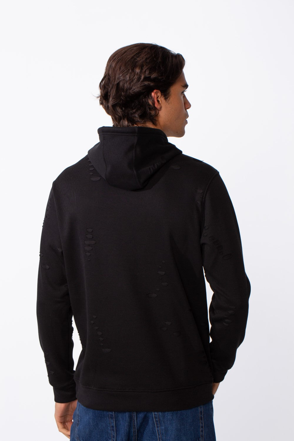 Rear view of a man wearing a black ripped slim fit kangaroo pocket hoodie and blue jeans.