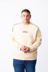 A man wears a cream-colored big size melton sweatshirt with black piping and a DESTROY graphic.