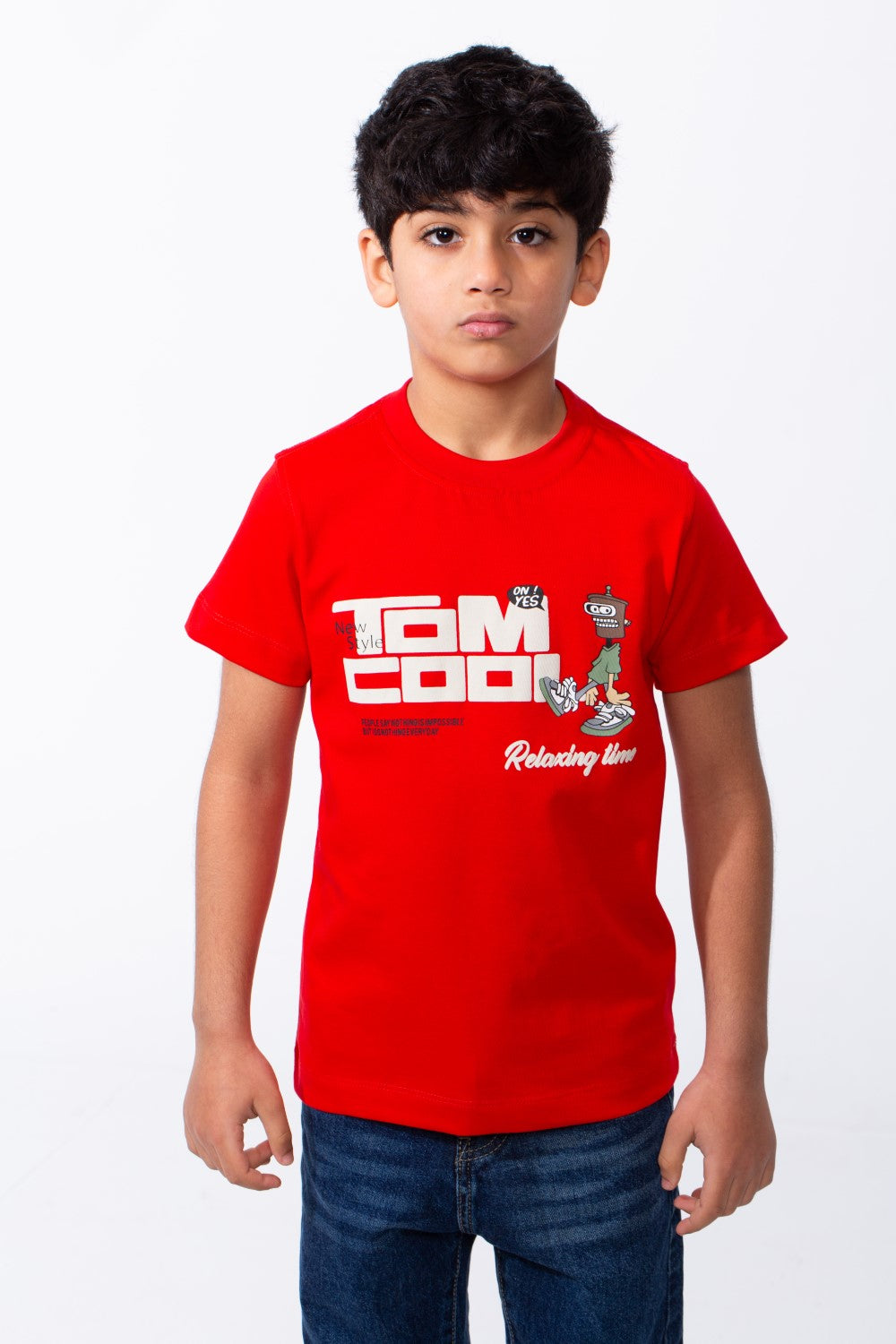 A young boy wears a red ribbed crew neck t-shirt with a white graphic print and blue jeans.
