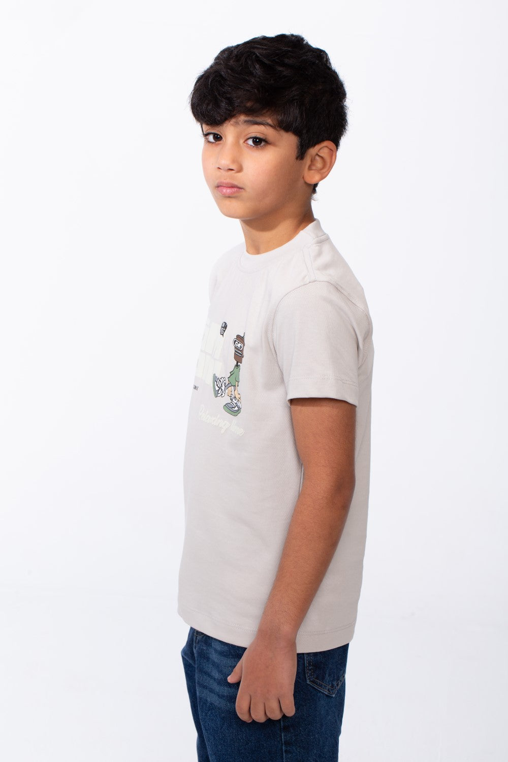 A boy wears a light grey ribbed crew neck t-shirt with a playful graphic on the front.