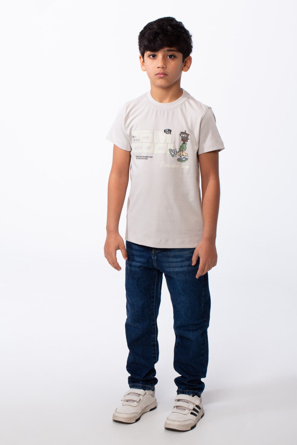 Boy's ribbed crew neck t-shirt in light beige with a playful graphic, paired with blue jeans.