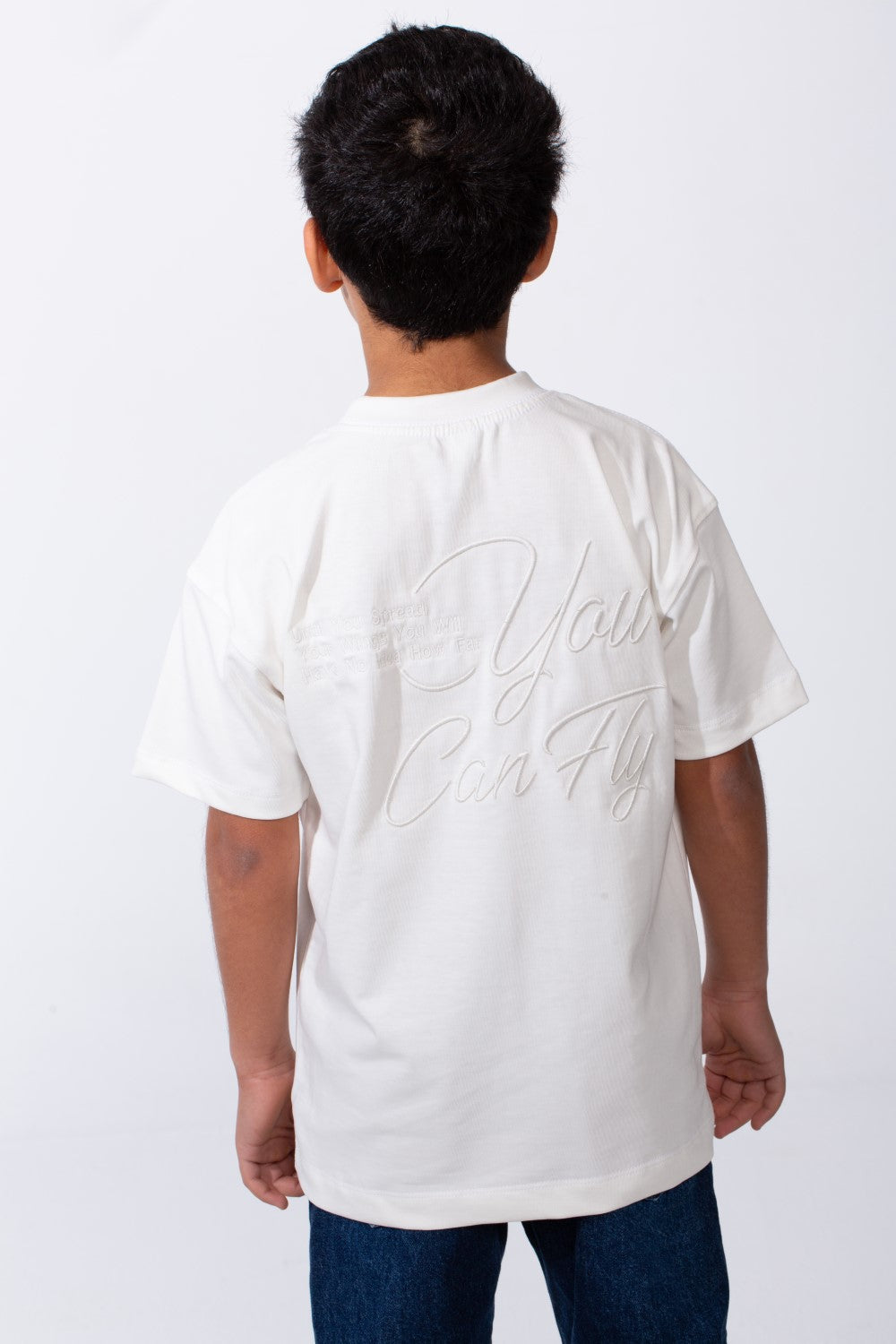Back view of a boy wearing a white oversized crew neck t-shirt with typography embroidery.